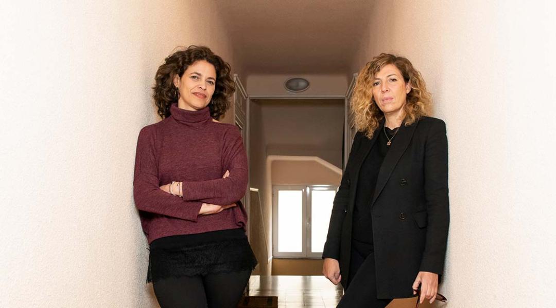 Yolanda Serrano (left) and Eva Leira (right) pose at the entrance of their office in Madrid. 
