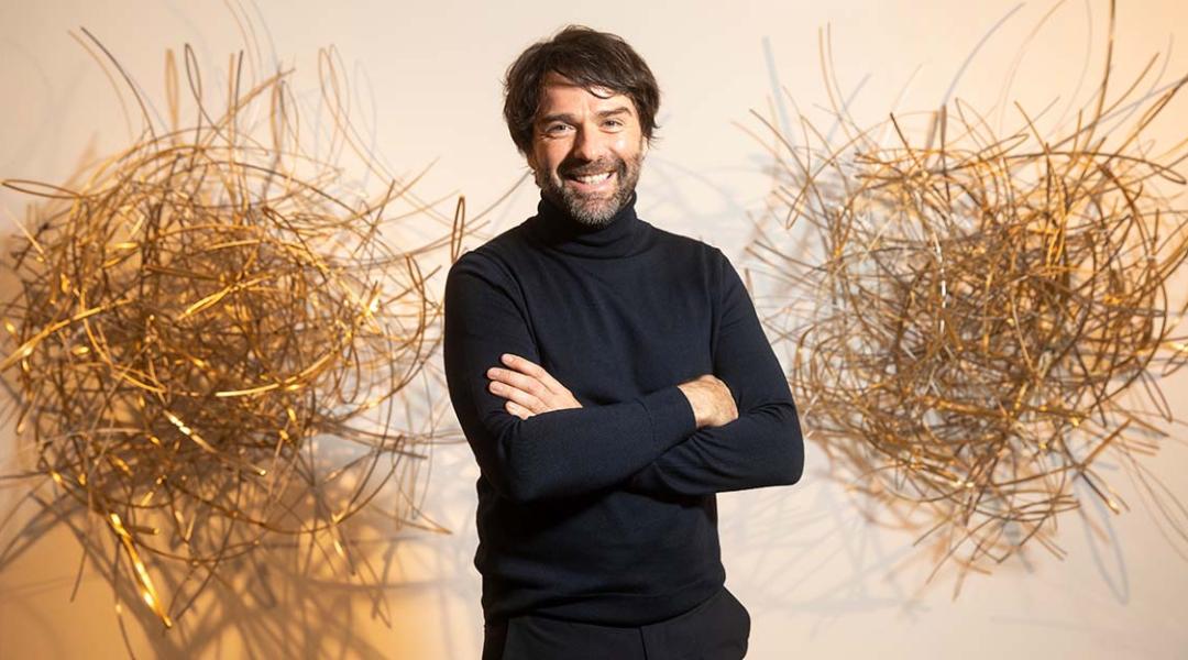 El escultor David Rodríguez Caballero posa sonriente junto a una de sus obras